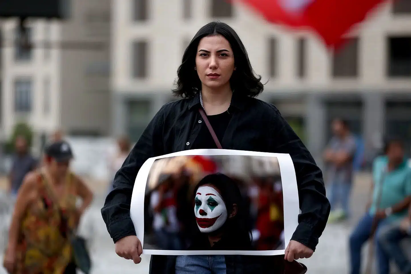 Den libanesiske demonstrant Cynthia Aboujaoude holder et billede af sig selv, hvor hun er sminket som Joker. Det sker, fordi hun og andre demonstranter kræver bedre leveomstændigheder og ønsker et opgør med de politikere, der har taget monopol på magt og indflydelse.