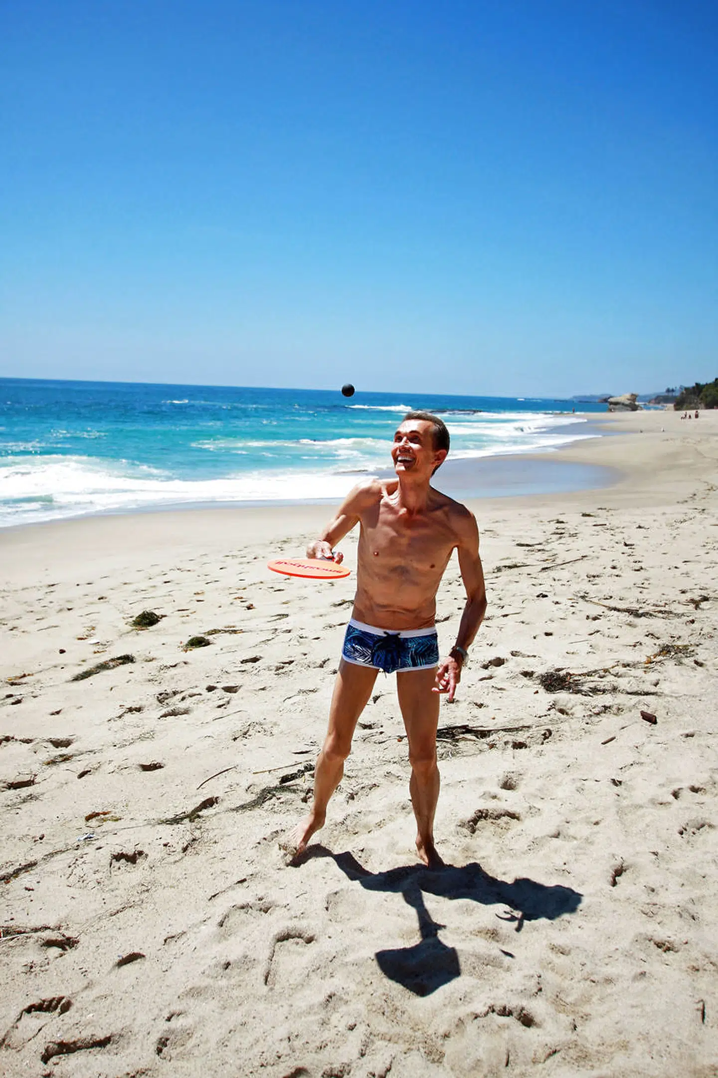 Strandtennis i solen med bølgerne som baggrund. Ole Henriksen og hans mand elsker strandsport.