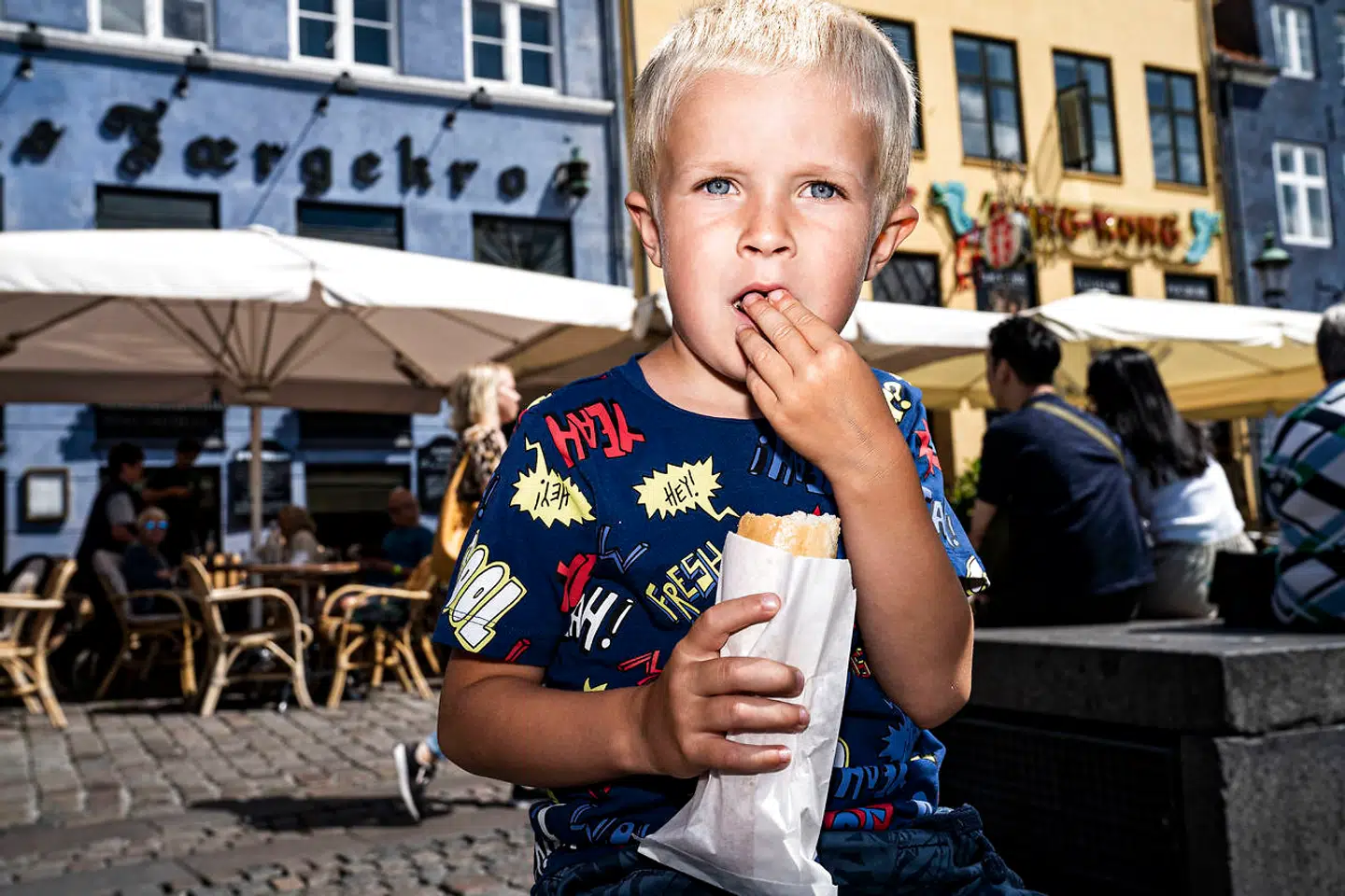 Selvom Michelin-restauranter tjener flere penge end før på udenlandske turister, skal vi huske det brede publikum, vurderer Dansk Erhverv. Her ses en meget ung mand med en hotdog i Nyhavn i København.