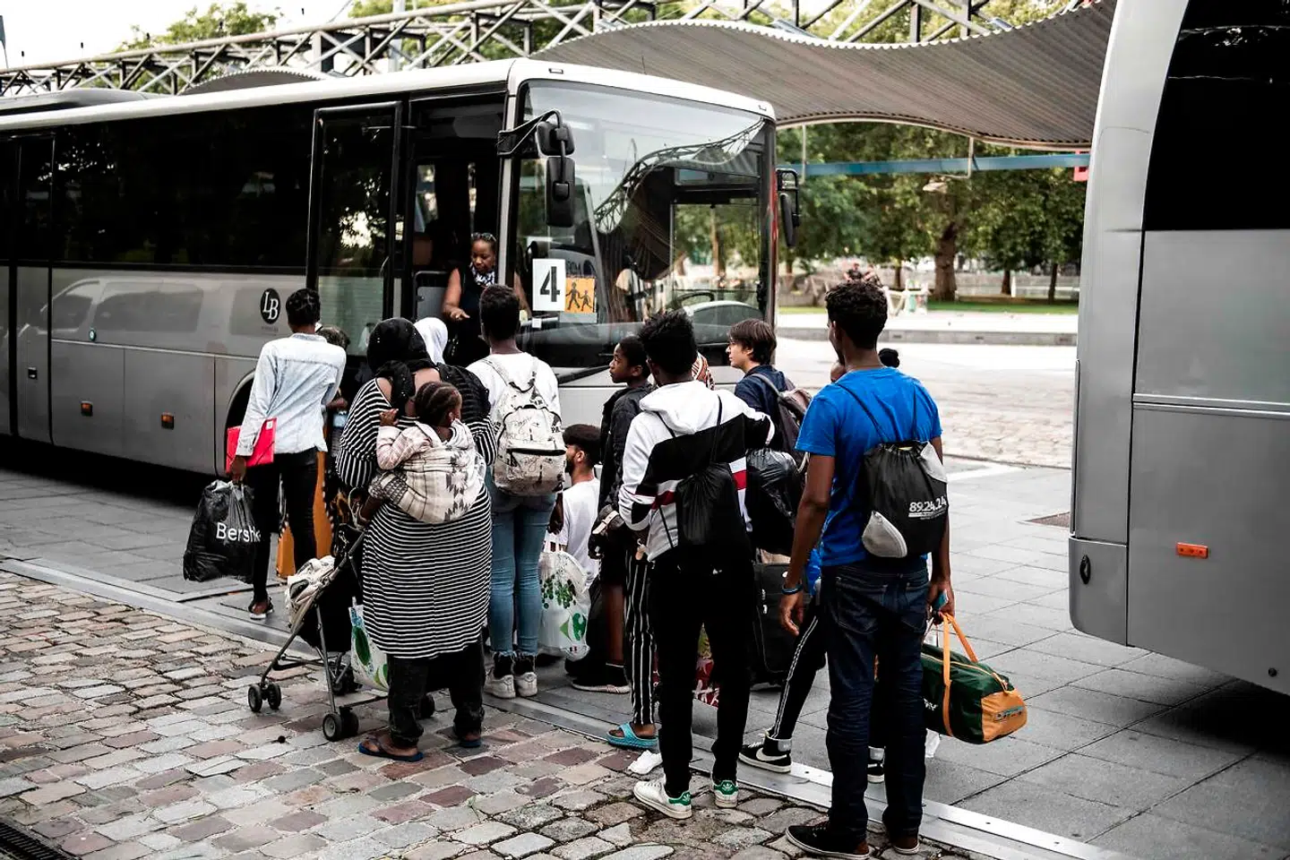 Migranter venter på at komme ombord på en bus ved en lejr i La Villette Park i Paris. Nu vil de franske myndigheder stramme udlændingepolitikken i landet.