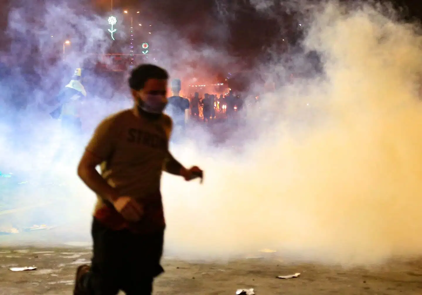 En demonstrant løber fra tåregas under protesterne mod Iraks regering i den shiamuslimske by Kerbala i Irak, syd for Baghdad. Søndag gik demonstranterne til angreb mod Irans konsulat i byen.