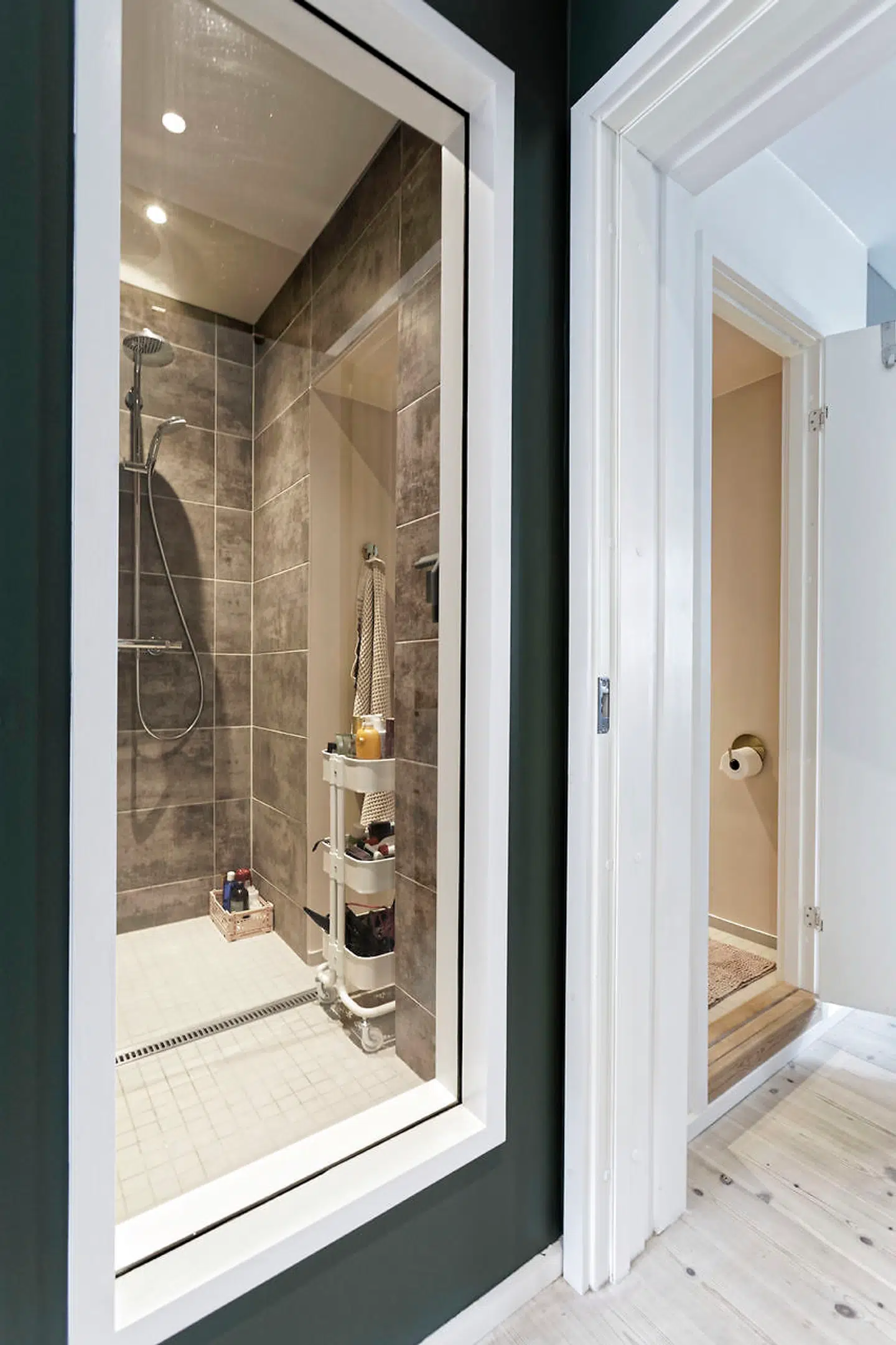 Alt i lejligheden er udskiftet, herunder badeværelset, hvor bruserummet som en overraskende feature har høj rude mod soveværelset. IKEA-vognen med cremer m.m. har erstattet et tidligere dominerende skab på toiletvæggen.