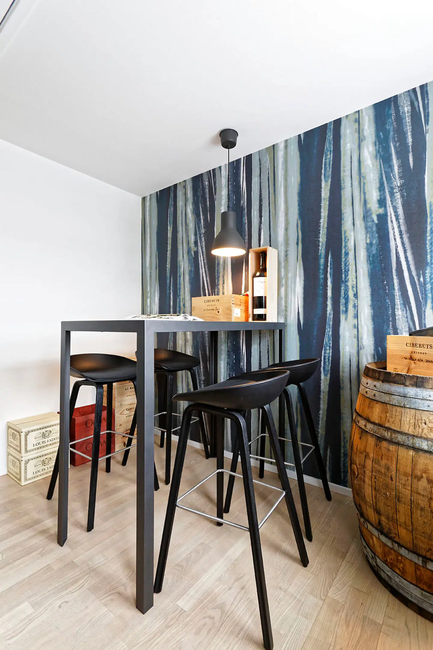 Til hygge med gæster findes et højbenet bord udført af Ole Brink Jensen med fliser fra Boelskifte Interiør & Design og barstole fra Hay i vinrummet, som tidligere var teenageværelse. Væggen er beklædt med tapet fra Black Edition.