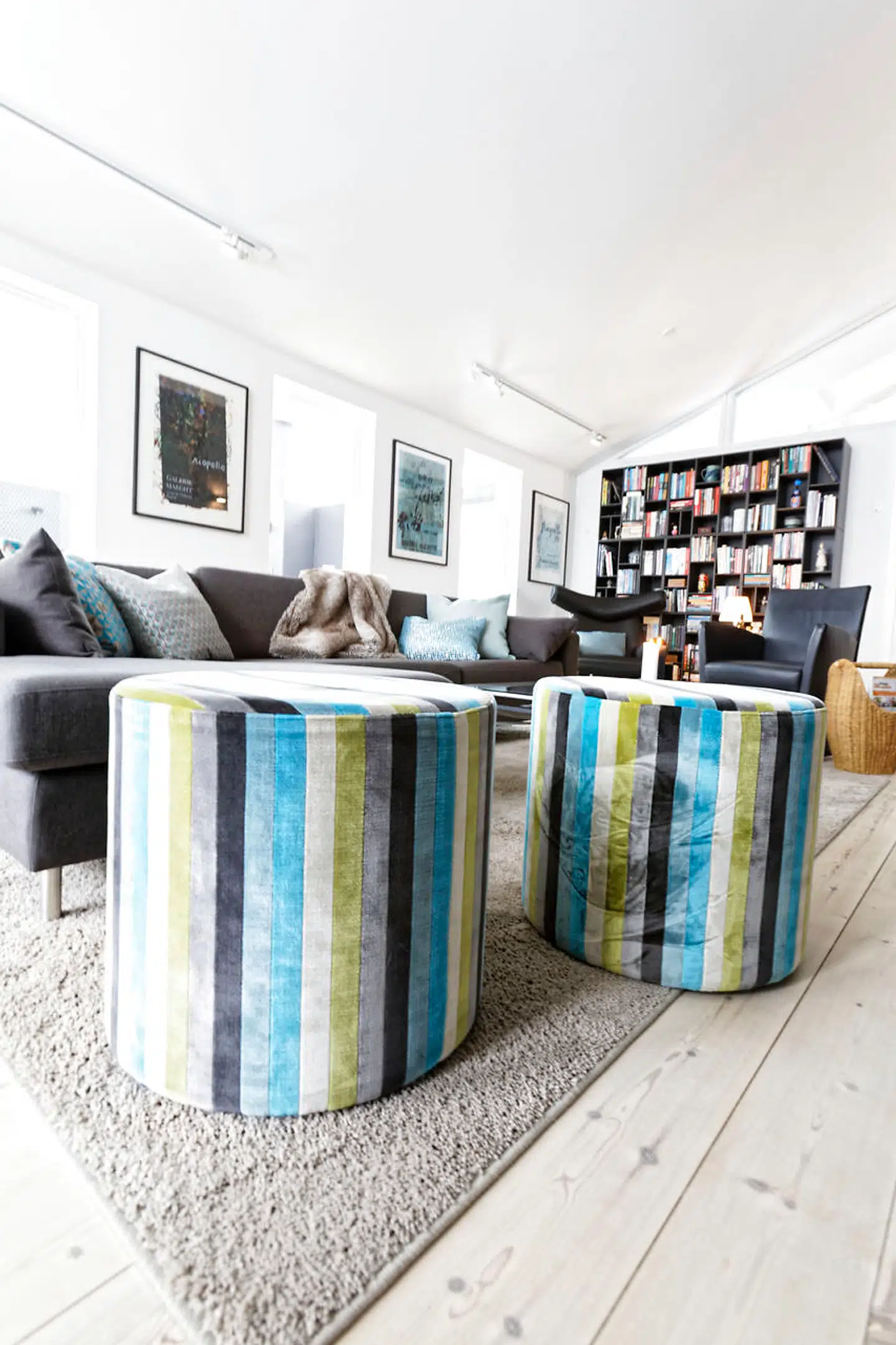 I stuen med åbent til kip er der blågrå kulører, mørk Montana reol og læseplads i Hans J. Wegners Ox-chair på tæppet fra Ilva. Sofaen er fra Bolia, mens pufs og puder er fra Boelskifte Interiør & Design.