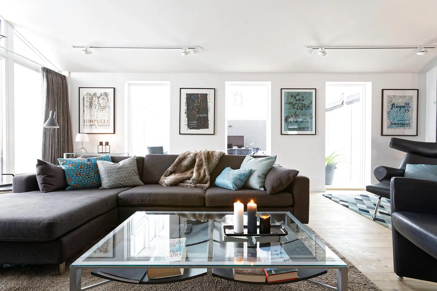 Stuen med det store vinduesparti mod syd er holdt i gråblå farvetoner med sofa fra Bolia og stribede puffer fra Boelskifte Interiør & Design. Lænestol og bord havde familien i forvejen.