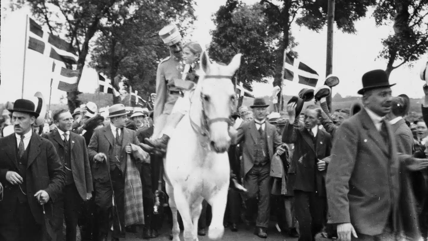 Christian X rider på den hvide hest Malgré Tout (Trods Alt) og løfter den ni-årige Johanne op ved æresporten ved Frederikshøj. 70.000 mennesker var strømmet til ceremonien.
