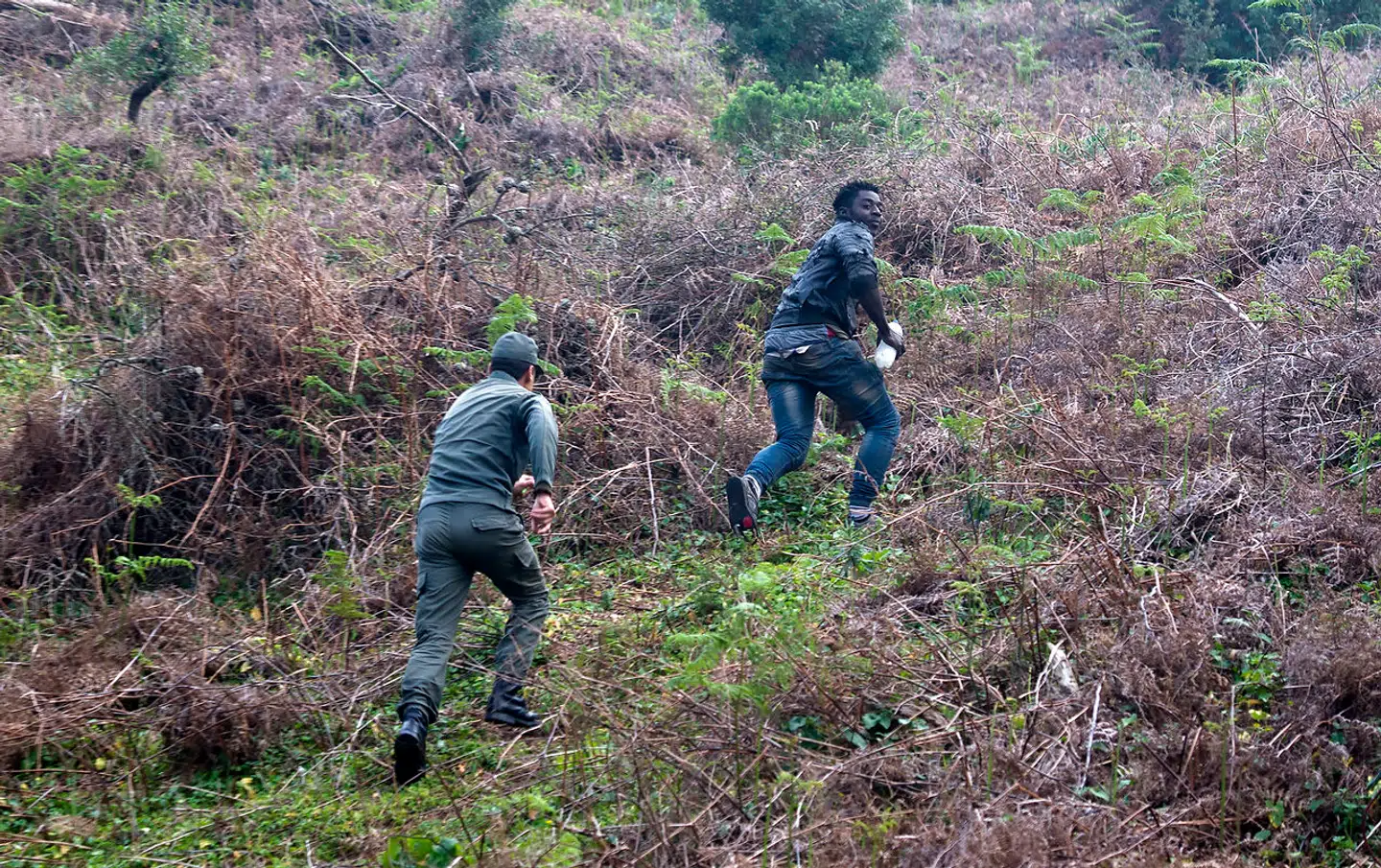En marokkansk betjent sætter efter en migrant efter et forsøg på at forcere grænsehegnet ved den spanske enklave, Ceuta.