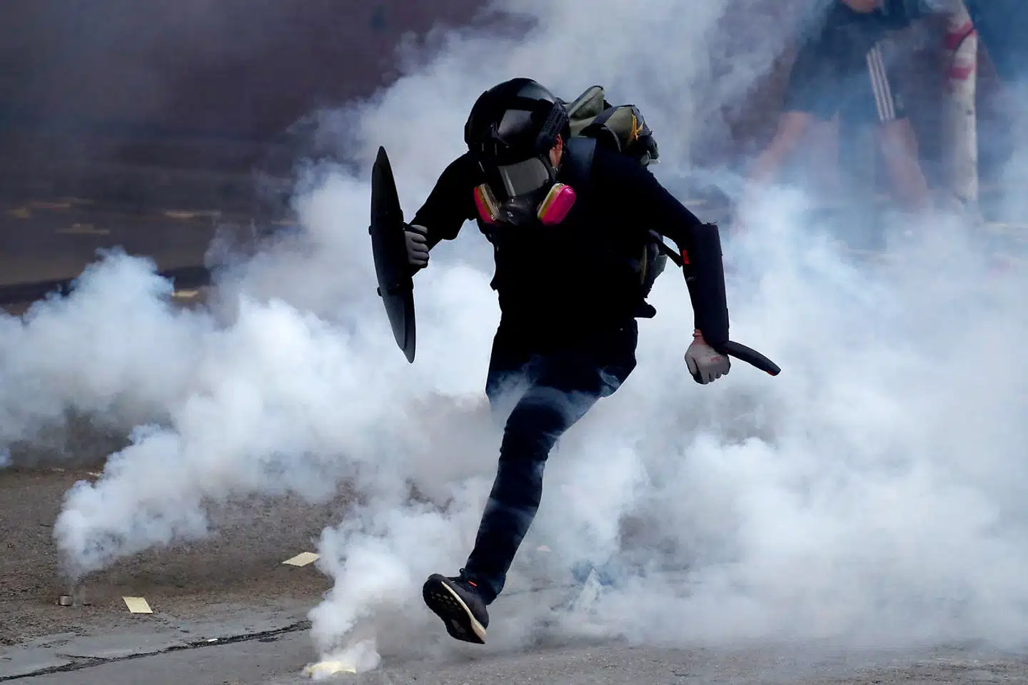 En demonstrant flygter fra politiets tåregas i Sham Shui Po-distriktet i Hongkong.