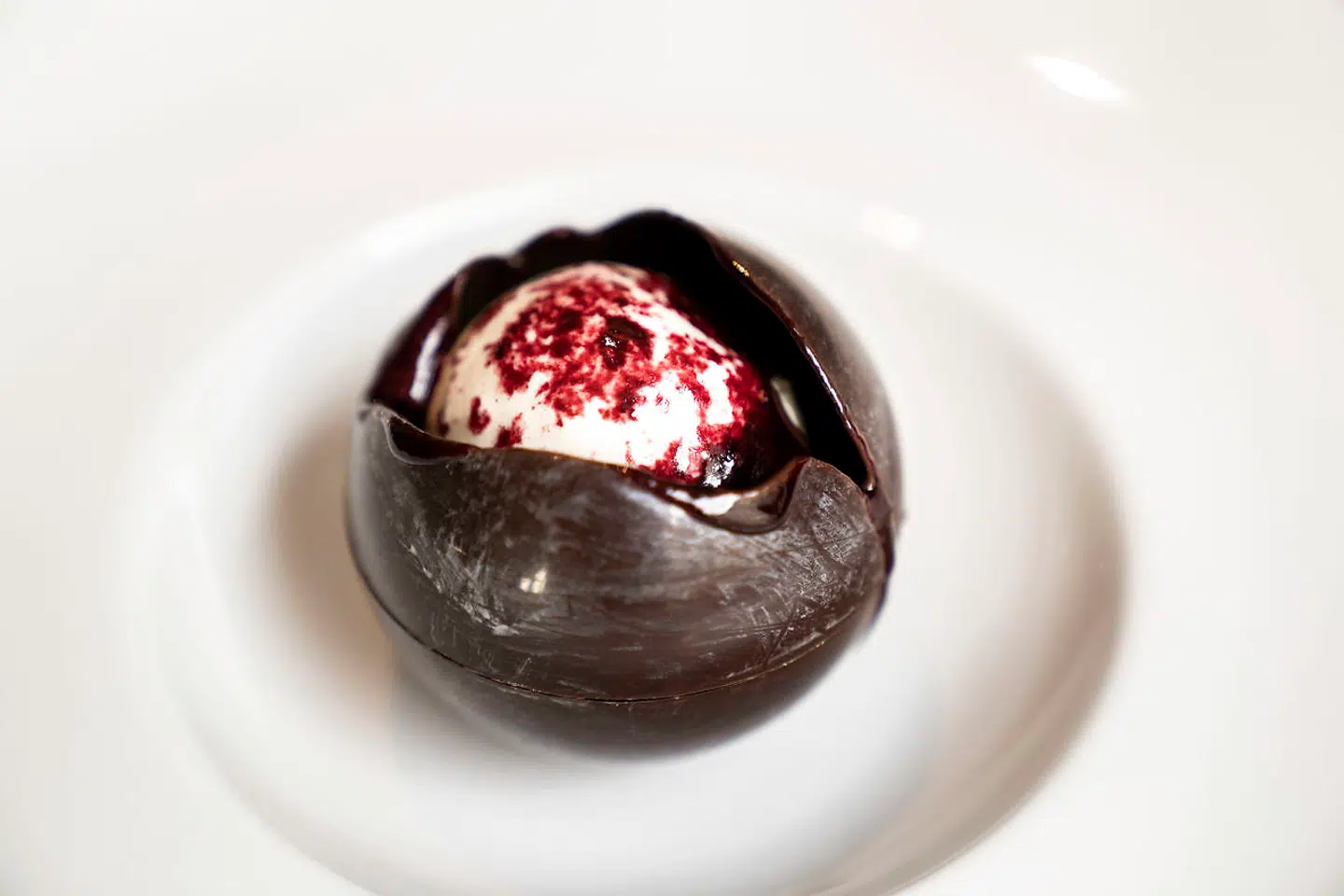 Desserten Kæmpe Eskimo kom i en tynd, rund sfære af mørk manjarichokolade, der ved servering blev overhældt med varm solbærkaramel, så skallen smeltede og blottede is og solbær. Foto: Maria Albrechtsen Mortensen