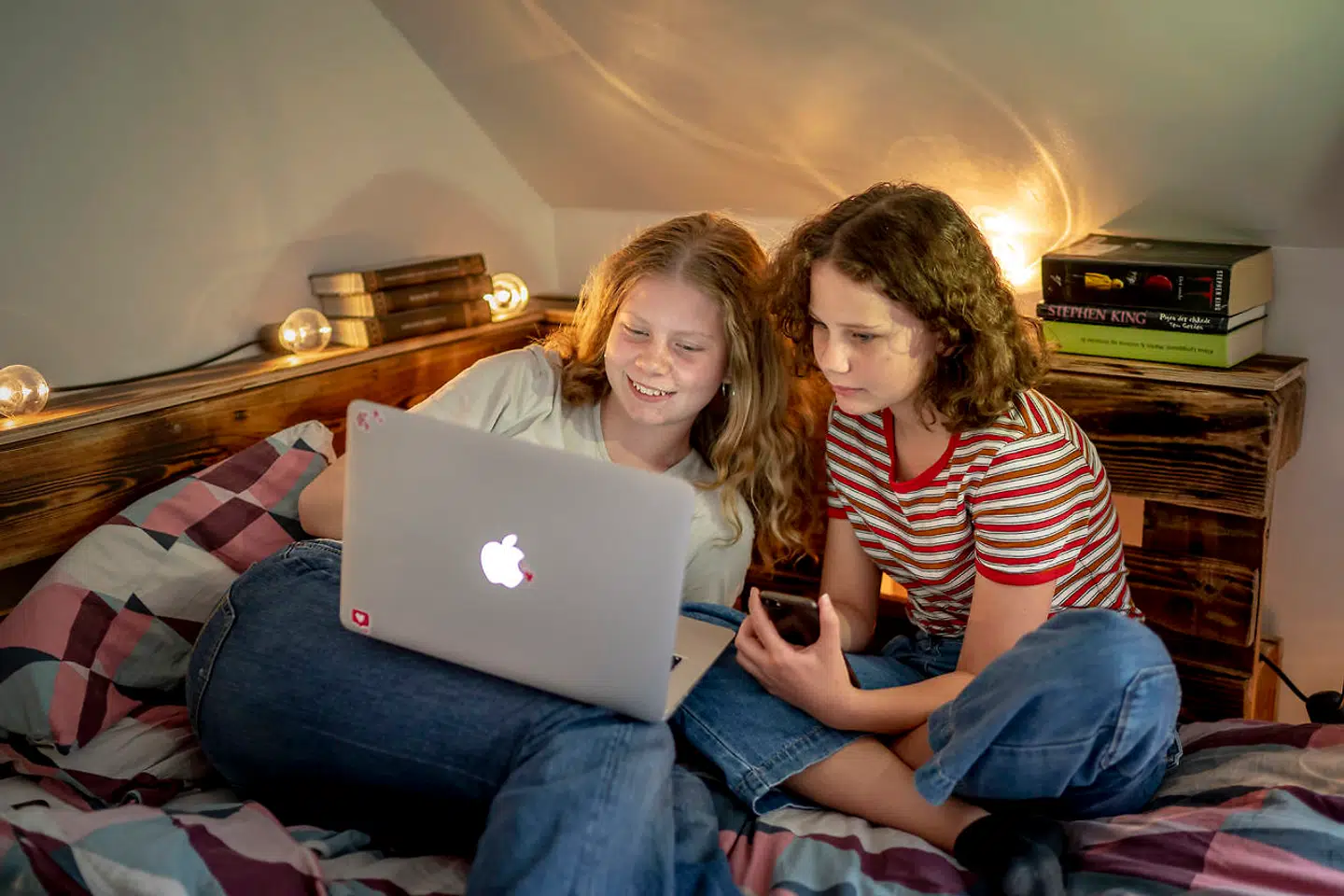 Selvom der ligger bøger klar på reolen, ender det som oftest med, at Vigga på 13 (tv.) og Katinka på næsten 11 - til deres fars frustration - sidder med Instagram eller Netflix på mobil og computer.