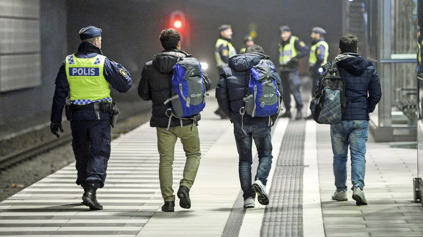 En svensk politibetjent eskorterer illegale migranter fra toget ved stationen i Hyllie uden for Malmø i november 2016.