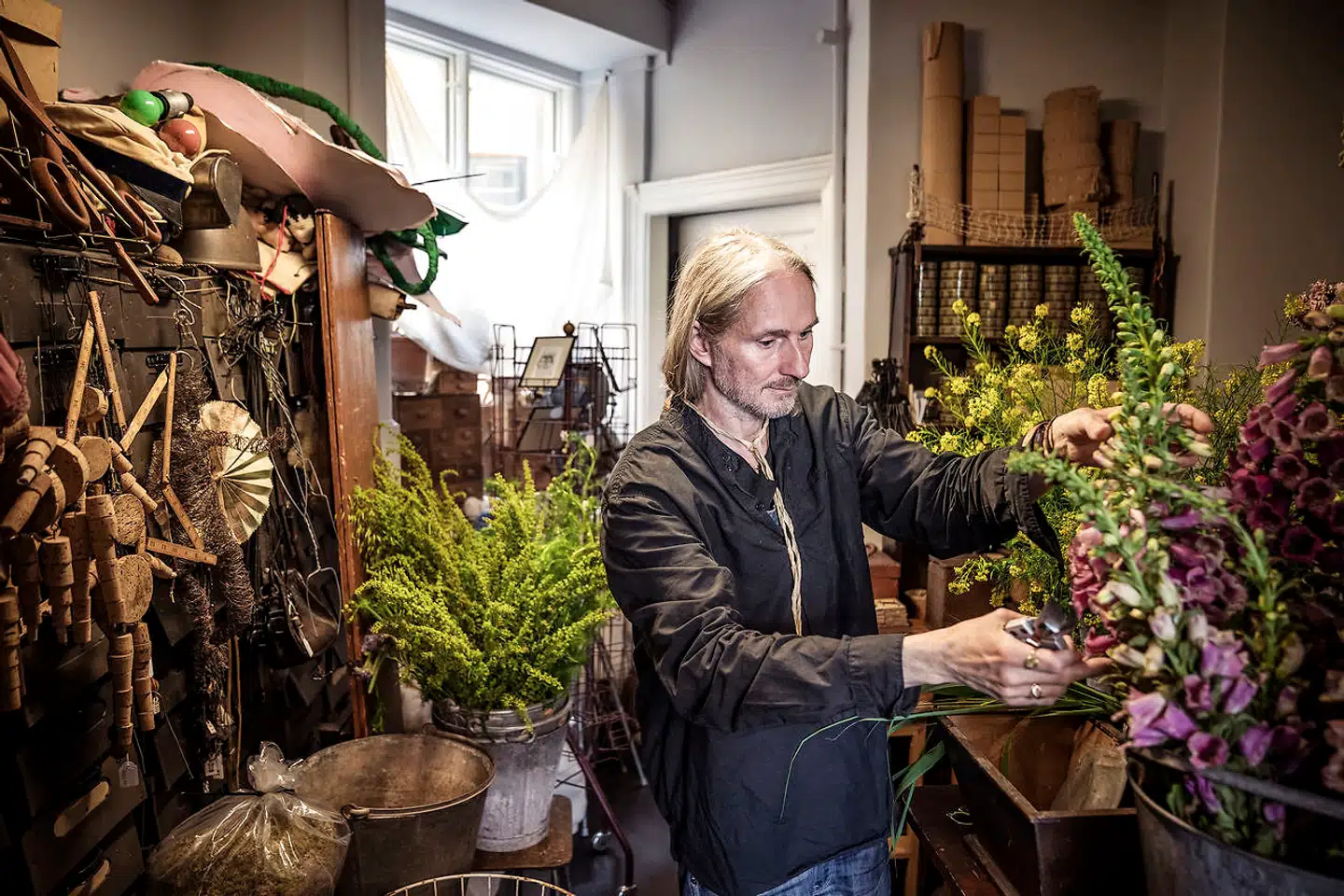 Leif Sigersen i sit værksted – omgivet af blomster og skæve ting, som han elsker.