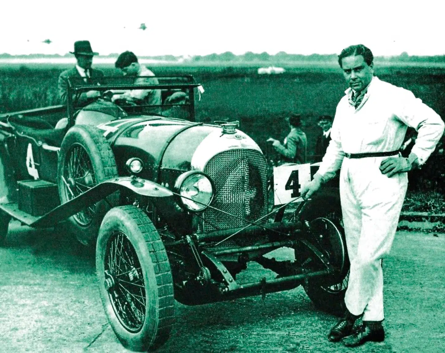 Woolf Barnato foran en Bentley-racerbil fra 1920erne. Han var millionær og racerkører, og han købte mærket i 1925 og ejede det frem til 1931, hvor børskrakket hev tæppet væk under markedet for luksusbiler.