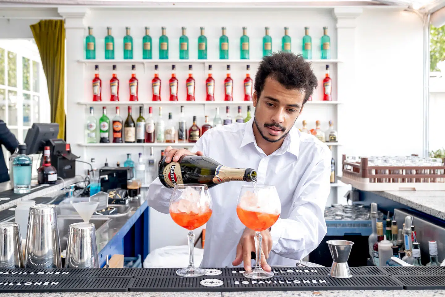 Restaurant Babylon serverer også cocktails. Blandt andet Aperol Spritz, der her er i færd med at blive hældt op.