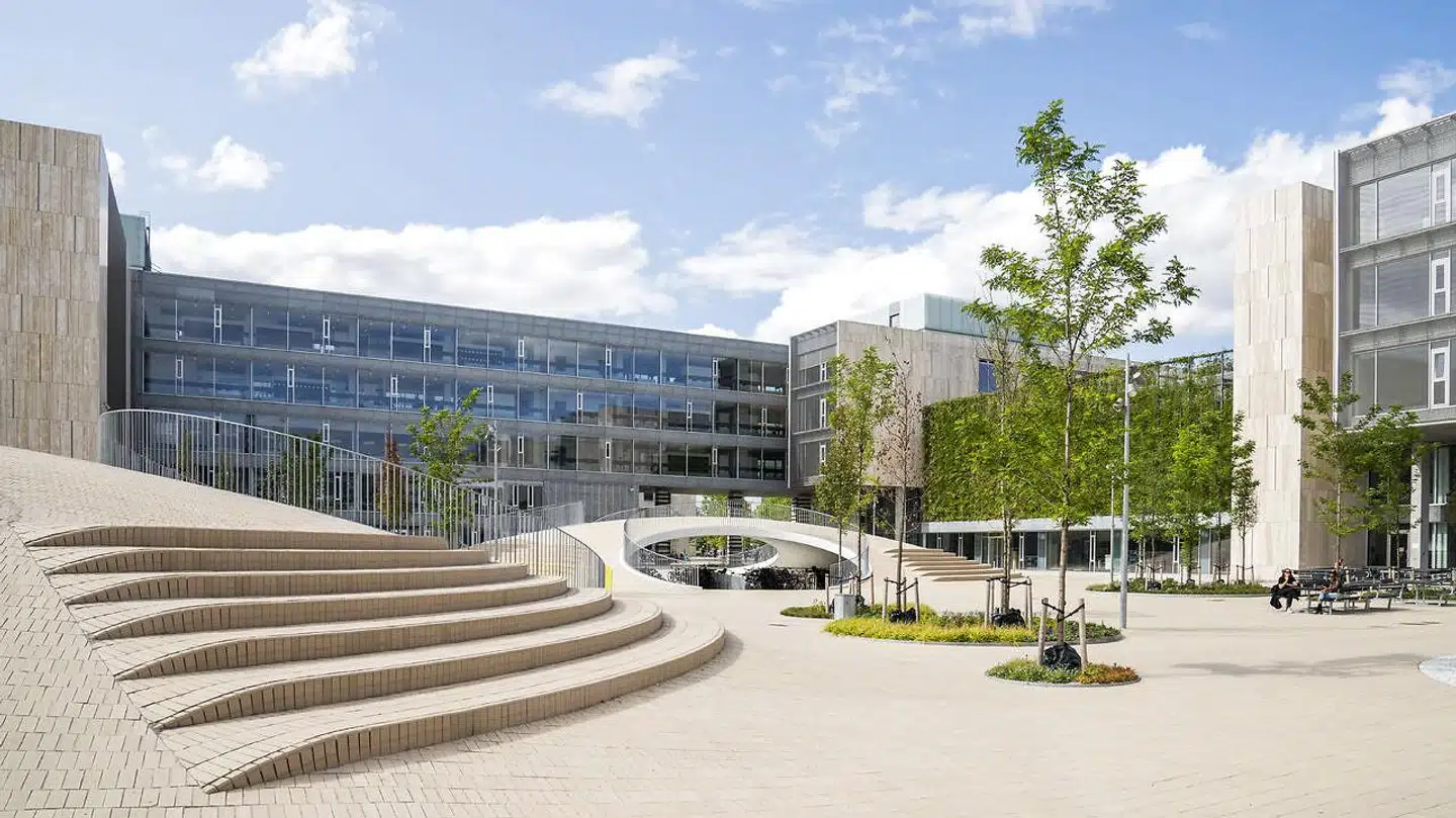 Med siddetrapper og hobbithuler til cyklerne byder Karen Blixens Plads velkommen til alle. Den smukke gule tegl passer perfekt til KUAs travertinfacader.