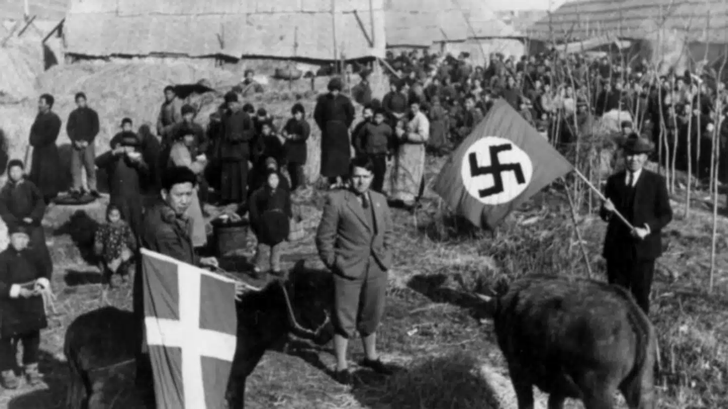Det rygtedes hurtigt blandt lokalbefolkningen at de fremmede flag på fabrikken kunne beskytte dem mod japanerne. Her står Sindberg med hagekorsflaget, som tilhørte hans tyske kollega Karl Günther (midt i billedet). Det er Sindbergs kinesiske tolk Li Yulin, der står med Dannebrog.
