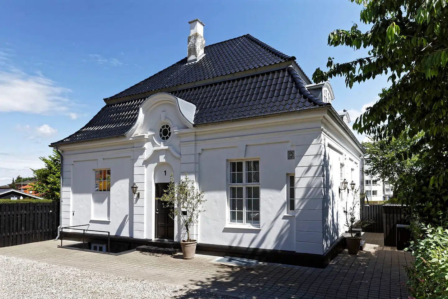 Stilen er bibeholdt på den statelige patriciervilla fra 1900. Den er hvidpudset med sortglaserede tegl og sort hoveddør.