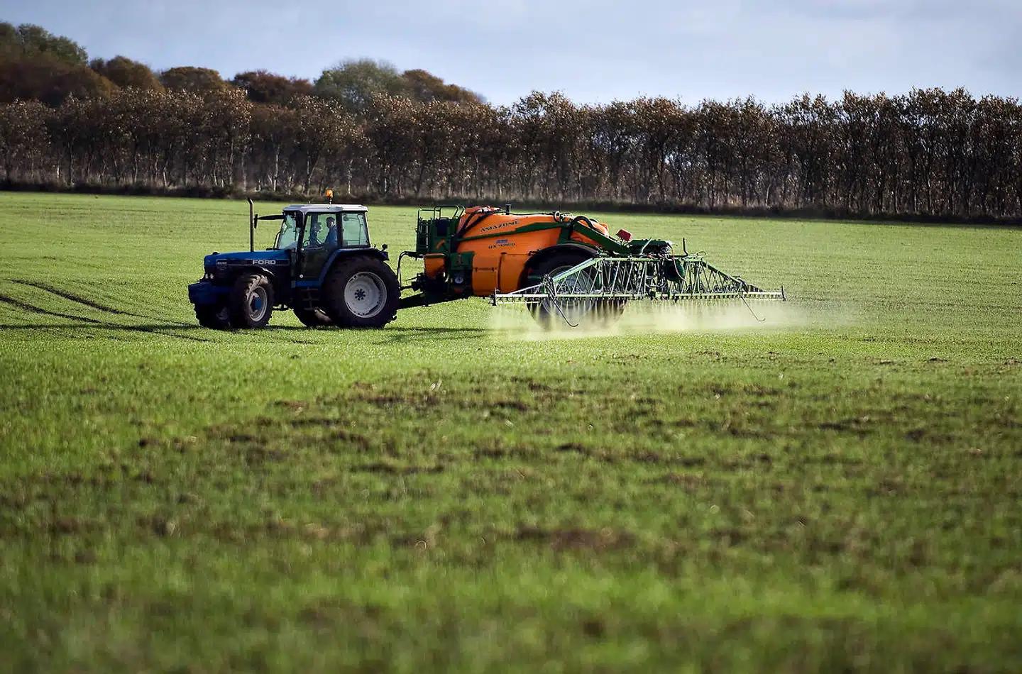 Markene sprøjtes. En landmand i sin traktor og sprøjtemaskine sprøjter markerne nær Nørhalne.