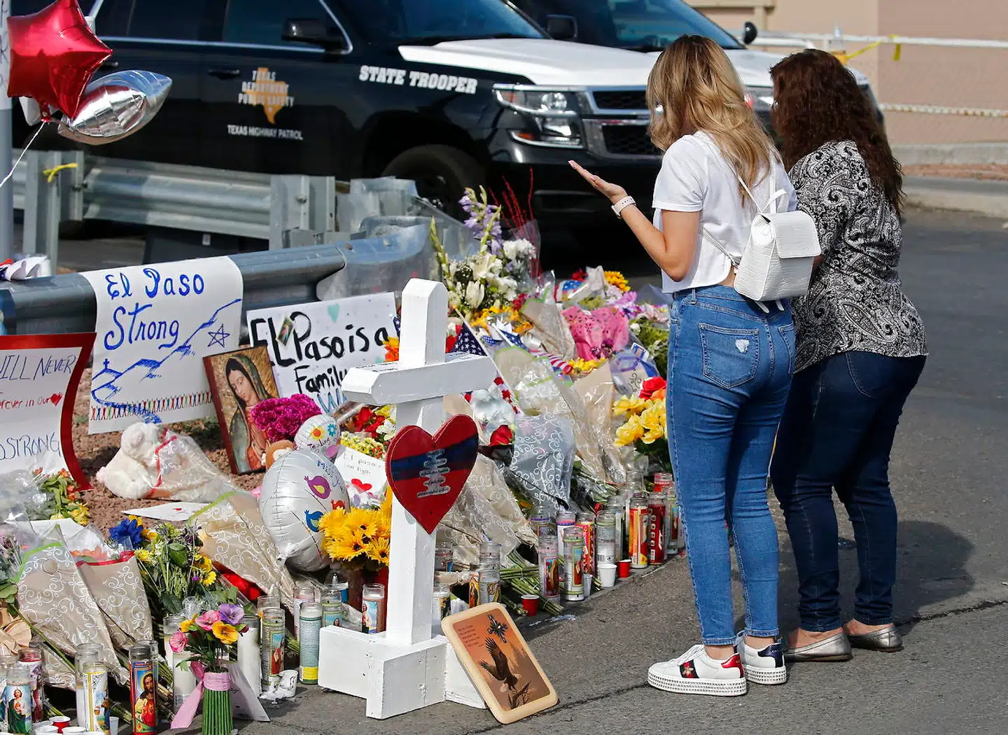 To kvinder er mødt op for at mindes de dræbte ved et mindested med blomster uden for supermarkedet Walmart i El Paso, Texas.