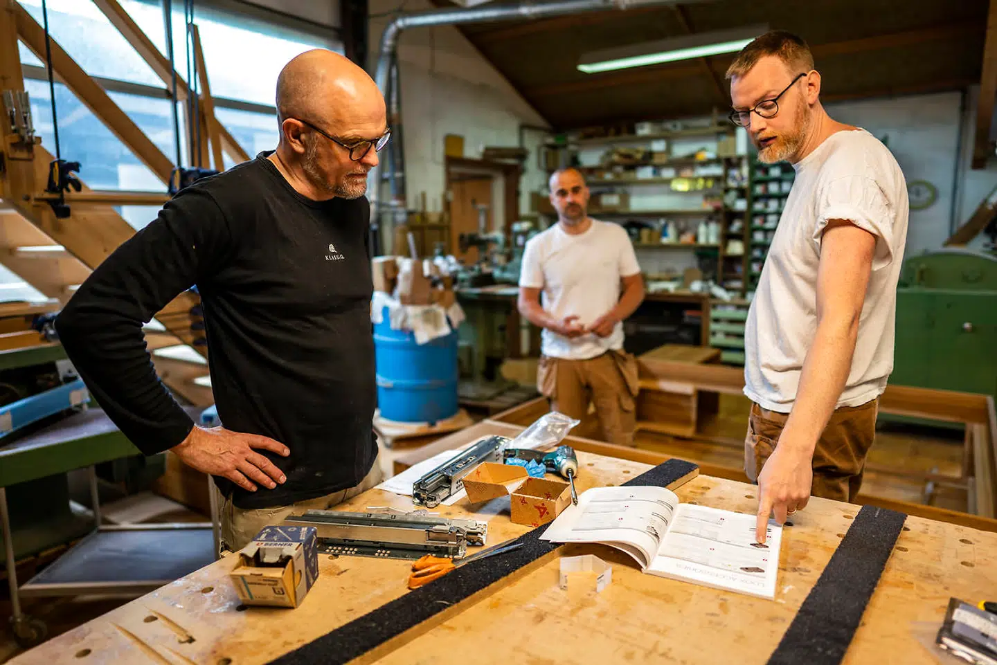 Fællesskabet på værkstedet er en vigtig del af Martin Arrilds dagligdag. Her er drøfter han med kollegerne Kresten og Thorbjørn de sidste detaljer i en stor ordre - et skræddersyet soveværelsemøblement i elmetræ, der skal installeres hos en kunde i Aarhus.