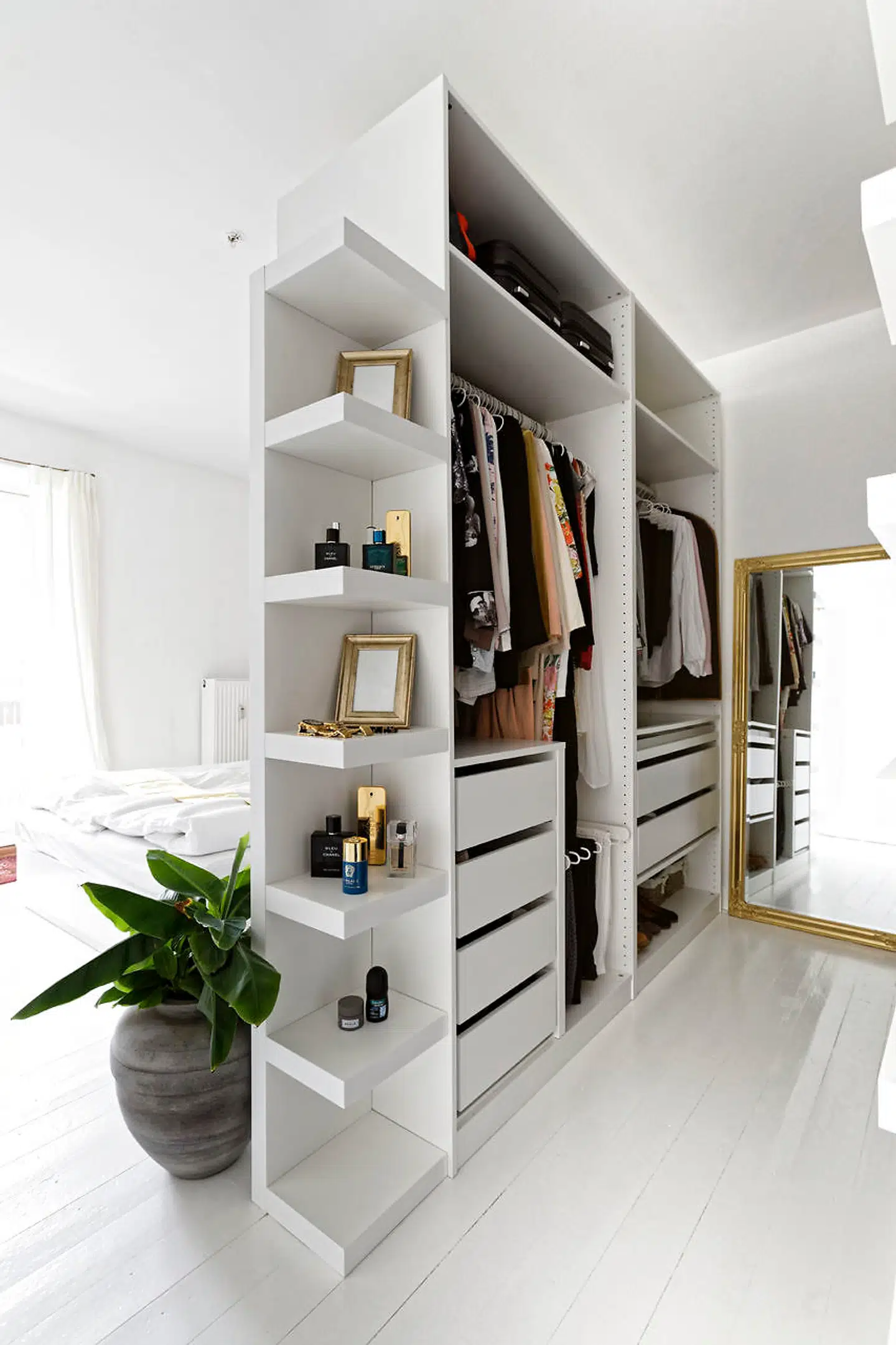 Drømmen om et walkincloset frem for indbyggede skabe er realiseret med et åbent IKEA-skab med bagsiden ud mod sengen tapetseret med murstenstapet fra rebelwalls.com. De åbne hylder bruges til billeder i rammer og parfumer.