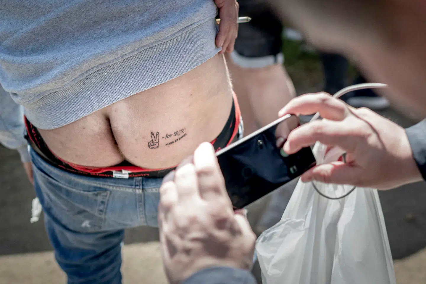 På Hjallerup Marked nord for Aalborg møder Rasmus Paludan - til sin store overraskelse - en mand, der har fået tatoveret partiets slogan "for sejr" med dertilhørende V-tegn på sin sin højre balde.