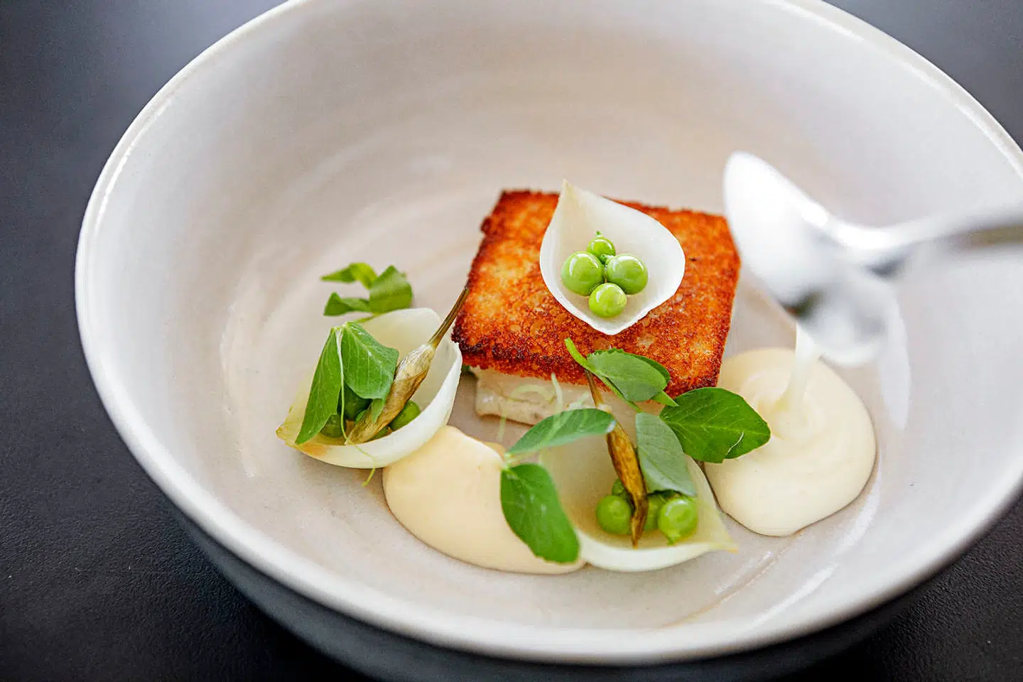 Rødtunge stegt på crouton serveret med ærter, løg og muslingesauce.