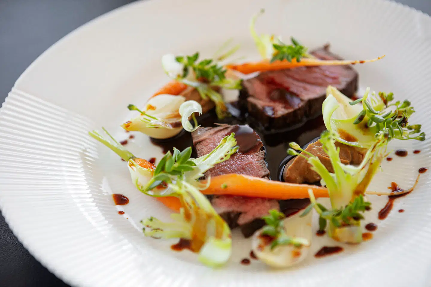 Oksemørbrad af dansk kødkvæg serveret med grønne asparges, spæde gulerødder, stegt blomkålspure og sauce bordelaise.