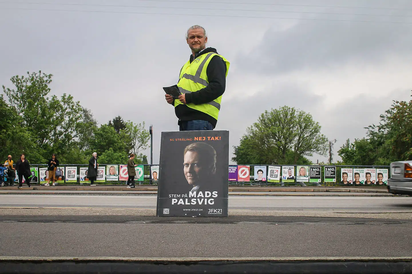 Et medlem af partiet JFK21 står med en valgplakat for partiformanden Mads Palsvig under valgkampen i Husum.
