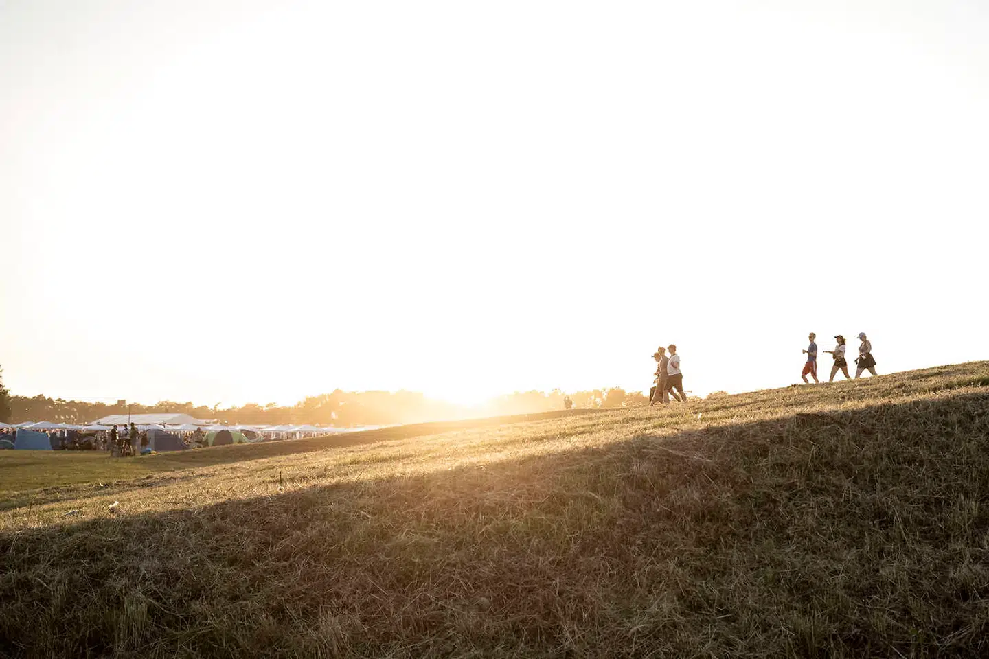Aftensol på festivalens første dag i campingområde øst. Folk begynder at søge mod de mange store fester, der er på pladsen. Roskilde Festival er for alvor begyndt.