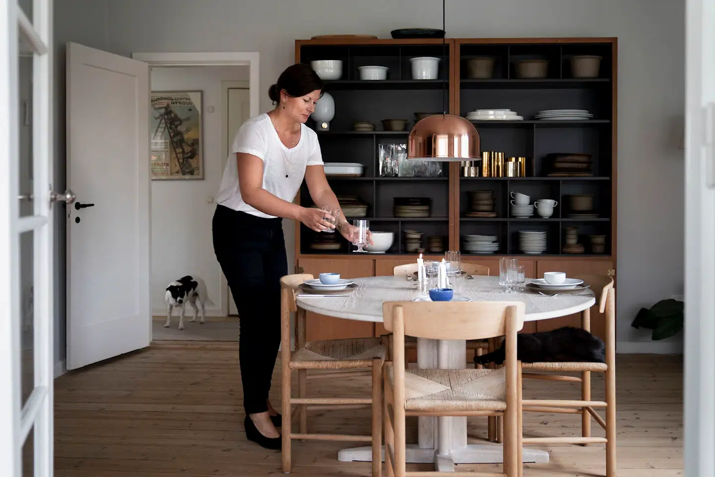 Isabel Brammer dækker bord med den nye version af Grethe Meyers STUB glas, der er kommet i produktion hos Holmegaard i år. Hele bagvæggen er Boligens Byggeskabe, som Grethe Meyer designede med Børge Mogensen. De var i produktion fra 1959-1980.