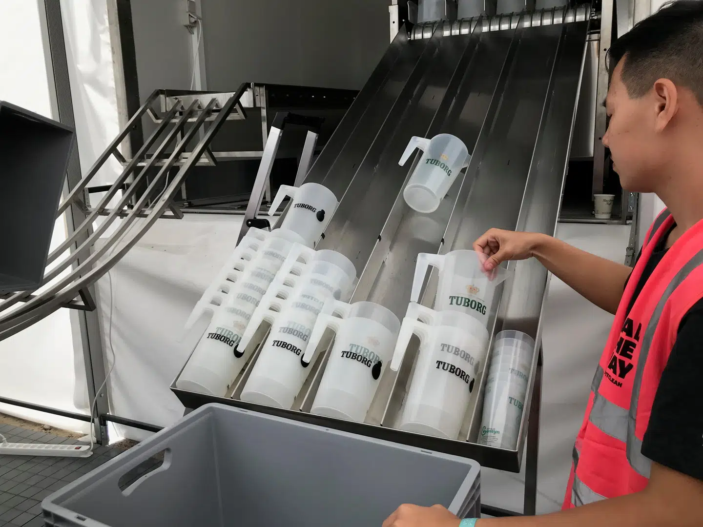 Når kander og krus er kørt gennem maskinen, hvor genbrugsplastikken er blevet vasket og tørret ryger de ned af en sliske, hvor frivillige står klar til at tage imod. Herefter pakkes 45 kander i en kasse, som tilsvarende kan rumme 220 krus af henholdvis 0,3 og 0,4 liter.