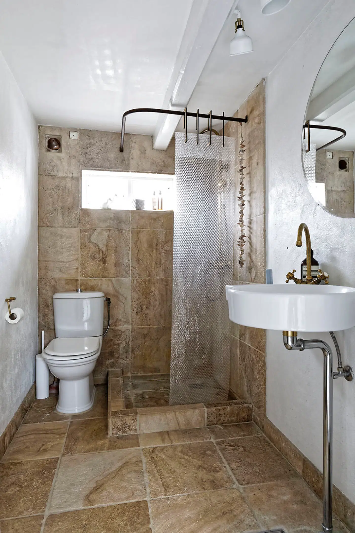 Badeværelset blev indrettet af de tidligere ejere med sandstensfliser og sanitet fra Les Campagnoles. I stedet for bruseforhæng har Lise Juel brugt en bane bobleplast.