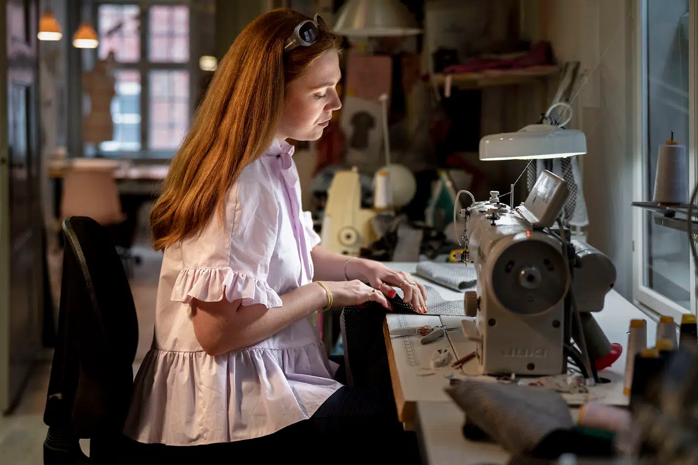 Sofie Sol Sjøstrand syede blot kjoler til sig selv. I dag designer hun til ikonisk butik i København. Her er hun fotograferet i sit værksted i Magstræde, hvor alle kjolerne bliver syet af hende selv og et par veninder.