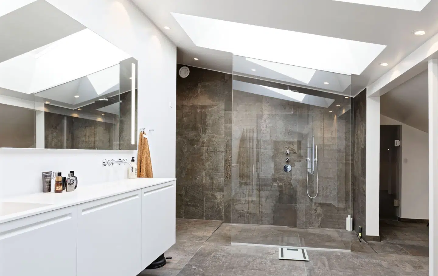 Husets badeværelser har store keramiske fliser med navnet Tatoo Oxidum fra Mosaikhjørnet. Bruserummet er afskærmet af en glasdør.