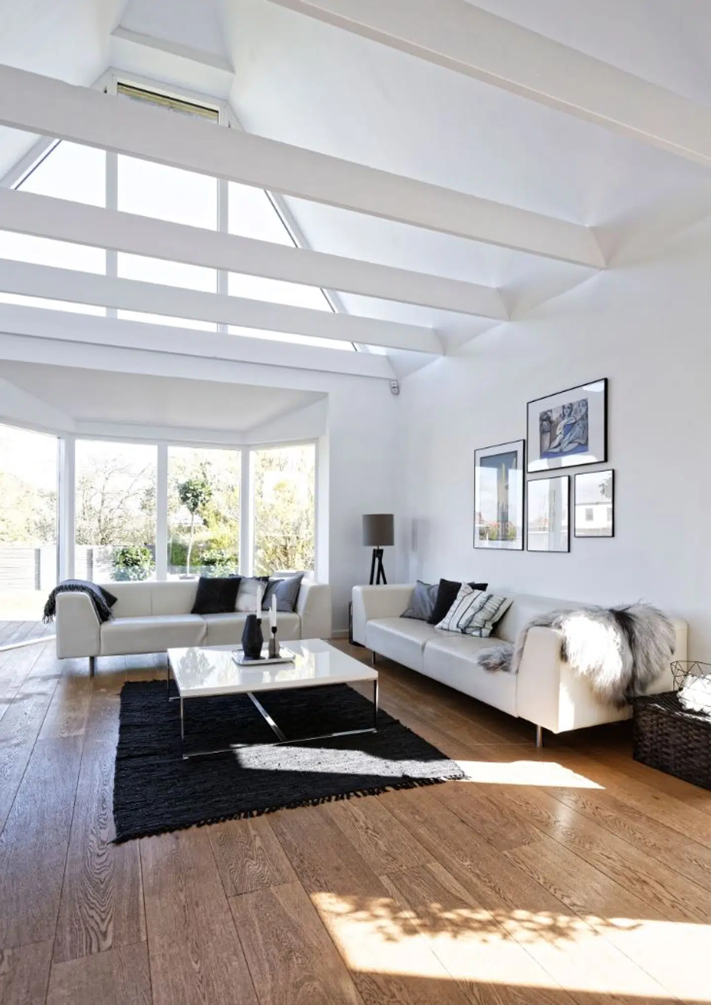 I karnapstuen er hvide lædersofaer og sofabord fra henholdsvis Bolia og Ilva. Puderne er fra Designerseye og Ilva og lampen fra Housedoctor.