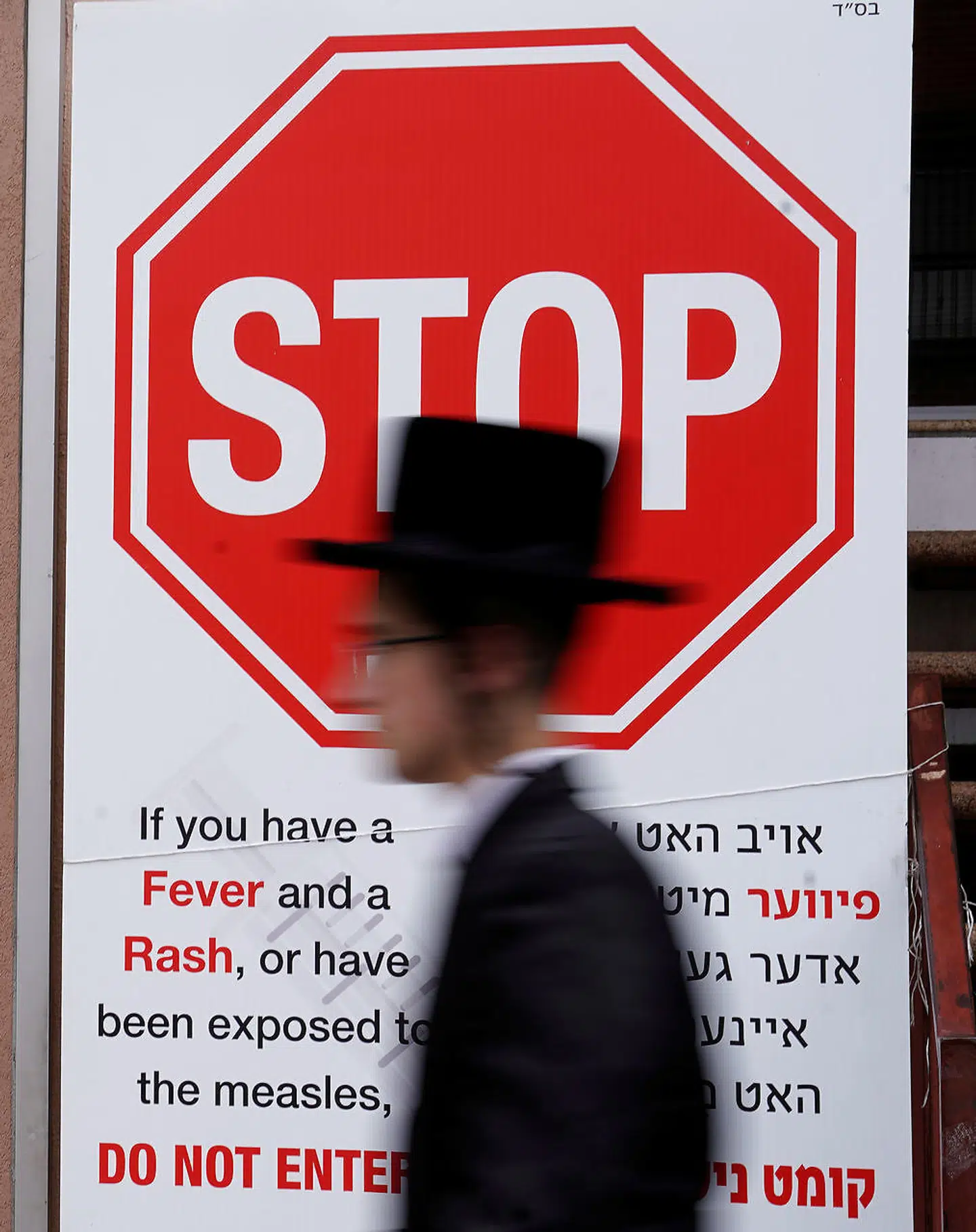 En person går forbi et skilt, som advarer om mæslingeepidemien, der er brudt ud i det ortodokse jødiske samfund i Brooklyn, New York.