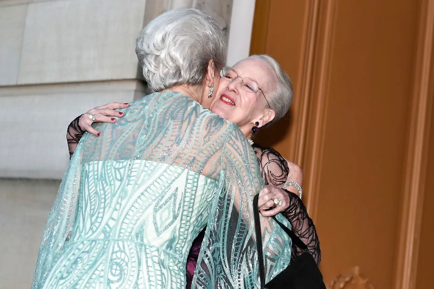 Aftenens vært dronning Margrethe modtog sin lillesøster prinsesse Benedikte med kram og kindkys, inden de to søstre stillede op side om side og lod sig fotografere af den fremmødte presse.