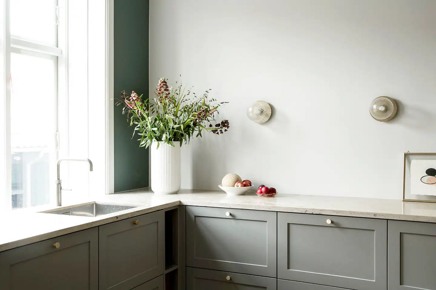 Parret ønskede sig et køkken, der var hyggeligt og havde en varm stemning. Det har de opnået med blandt andet et gråt snedkerbygget køkken fra Handcrafted Interior, en bordplade i jura grau marmor fundet hos Marmorgården og skulpturelle lamper fra Nuura, som giver et smukt spil og et blødt og behageligt lys.