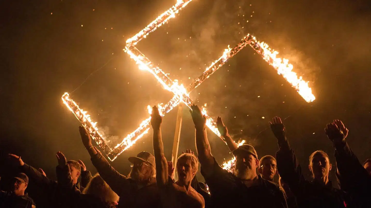 Tilhængere af den yderligtgående amerikanske National Socialist Movement hilser med strakt højrearm foran et brændende hagekors. Mødet blev afviklet på et hemmeligt sted i Georgia 21. april 2018.