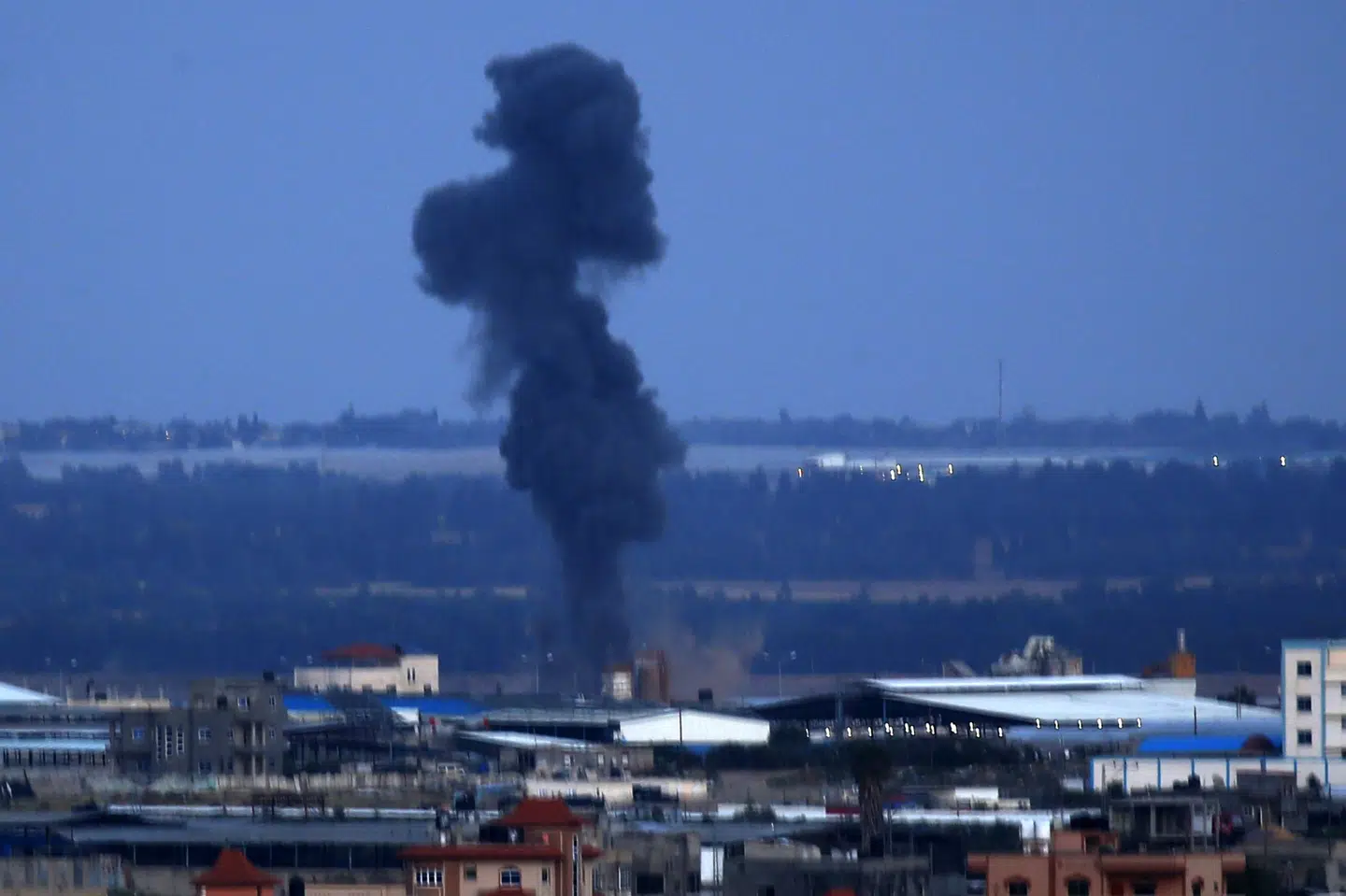Sort røg stiger op over bygninger i Rafah i den sydlige del af Gazastriben mandag aften. Israel har indledt angreb mod Hamas-bevægelsen som reaktion på et raketangreb fra Gaza, der slog ned i et hus uden for den israelske storby Tel Aviv tidligt mandag morgen. Said Khatib/Ritzau Scanpix
