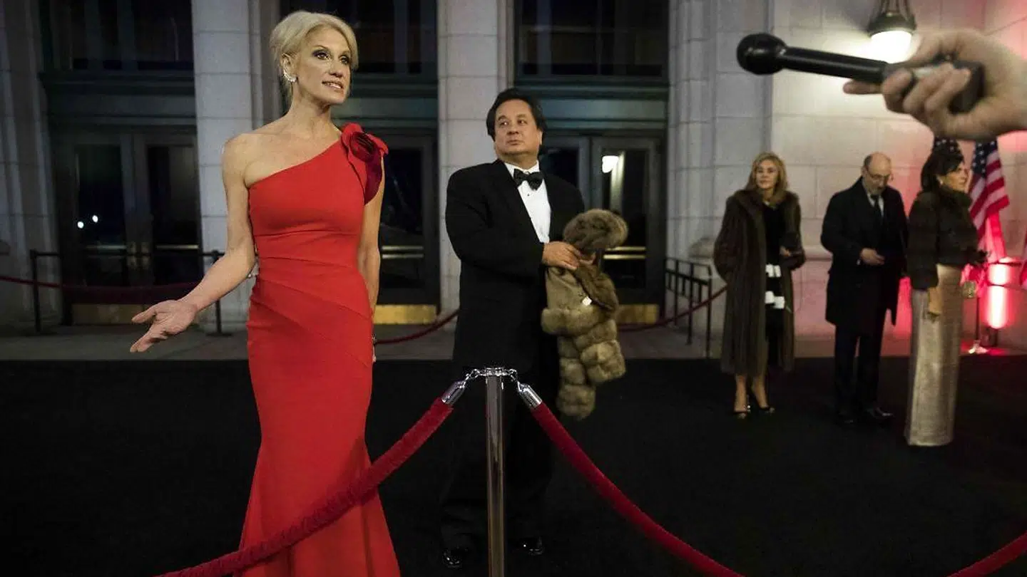 Trumps talskvinde og toprådgiver, Kellyanne Conway, taler til pressen i forbindelse med en middag for præsidentens donorer tilbage i 2017, imens hendes mand, George Conway, i baggrunden holder hendes pels.