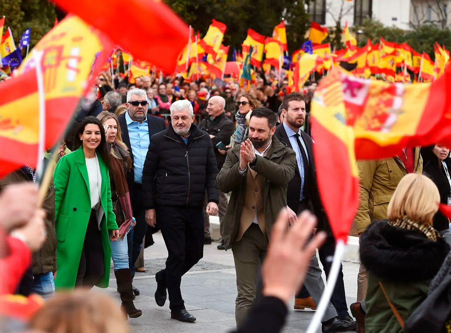 Santiago Abascal hilser på folkemængden omgivet af spanske flag under en demonstration i Madrid.