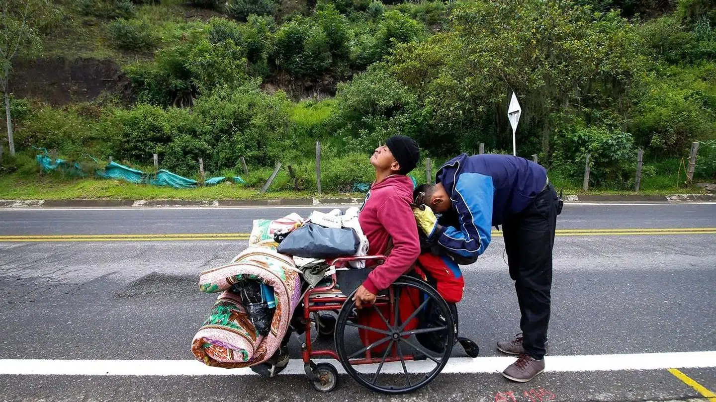 Den venezuelanske migrant Jefferson Alexis og hans far, José Agustin Lopez, som sidder i kørestol. Et kort stop, inden turen fortsætter til byen Cucuta og grænsen til Colombia.