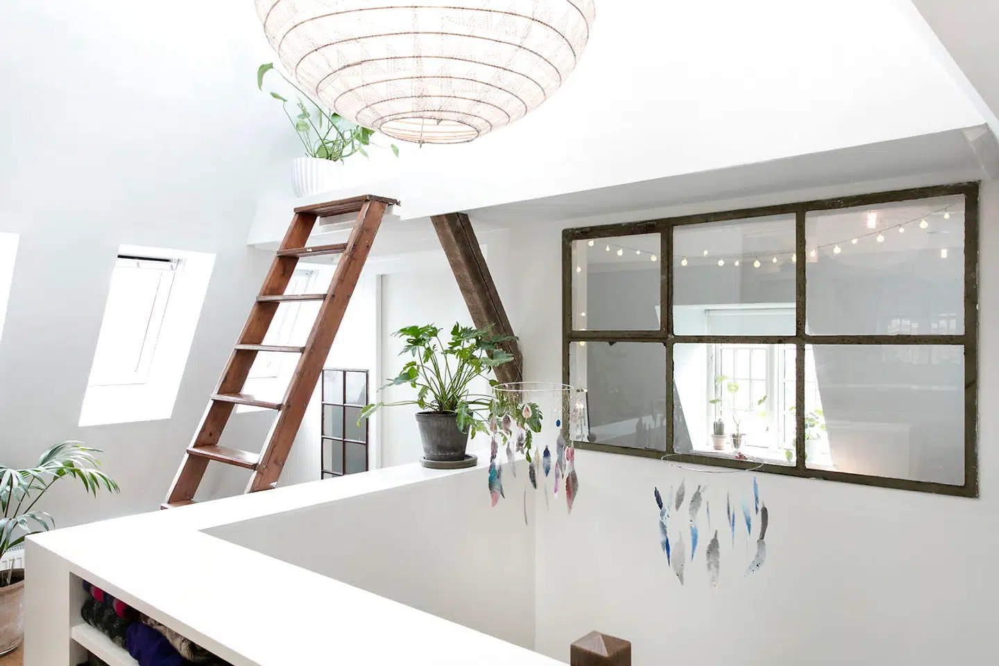 Det, der tidligere var et fællesrum, er blevet til et rum med tre funktioner: Et værelse til den ældste datter, en hems og et repos-rum med plads til klædeskabe. Det gamle vindue, der er blevet sat i væggen for at skabe lys gennem rummet, er fra Genbyg. Lampen i loftet er fra Paris au Mois d’Août, og de smukke fjerpyntværker er af Christina Winsløv.