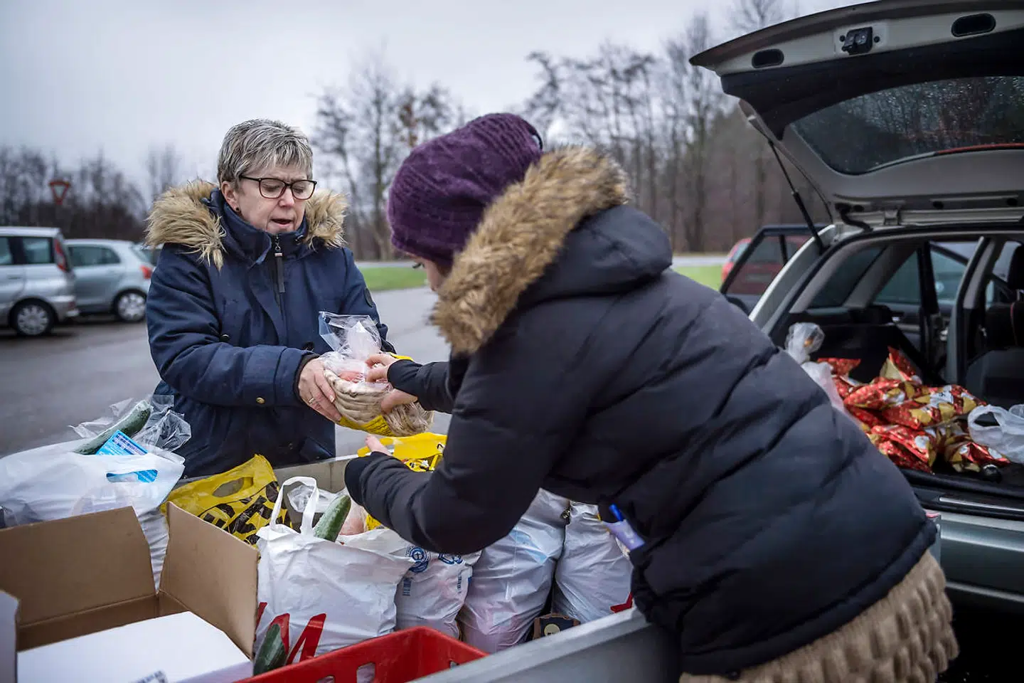 Susan fra Sjælsmarks Venner pakker poser med madvarer sammen med en af beboerne på parkeringspladsen foran udrejsecentret.