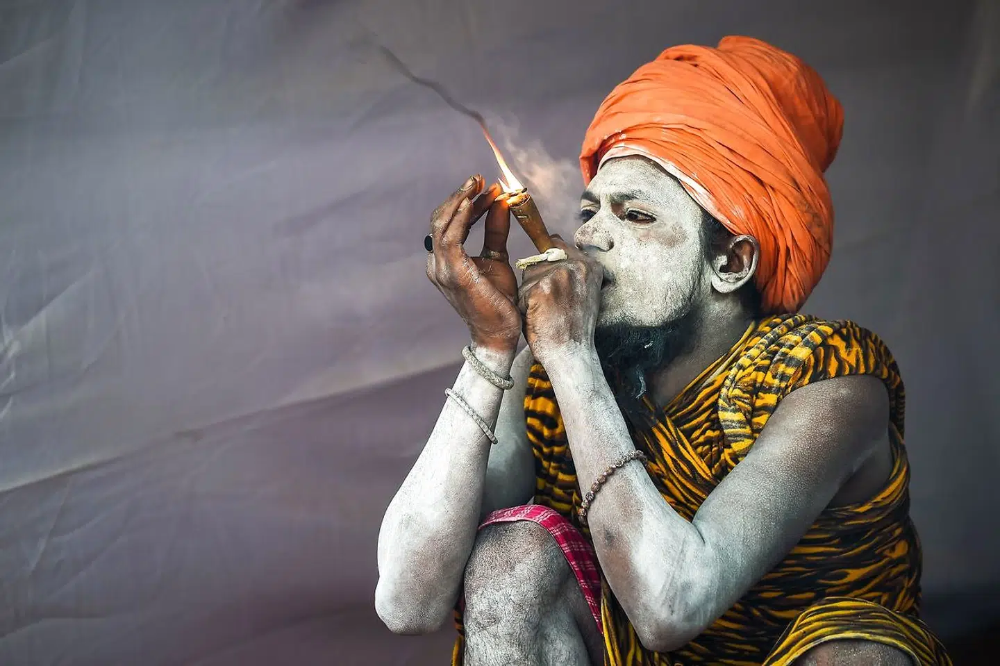 En indisk sadhu (hellig mand) ryger uden for sit telt under Kumbh Mela.