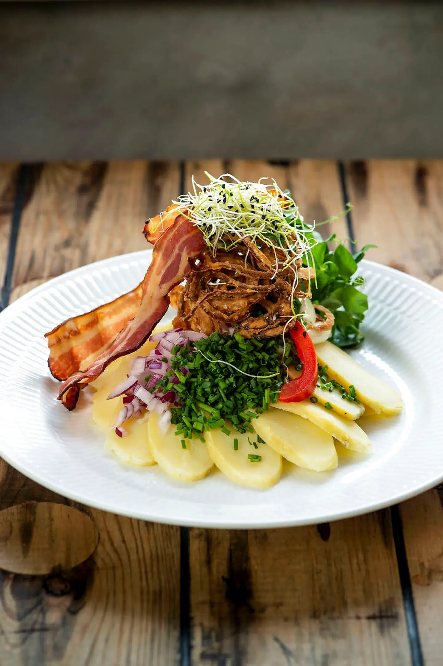 Tårnhøj kartoffelmad med friterede løg og bacon.