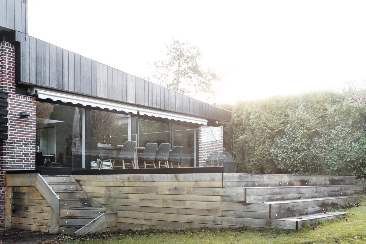 Efter at have fået sat vinduer fra gulv til loft ud mod haven og udsigten til sø og skov, fik Susanne Hermann og hendes mand bygget en stor træterrasse med brede trin, der følger den skrånende grund. Her er plads til masser af gæster, og den fungerer som ekstra leverum.