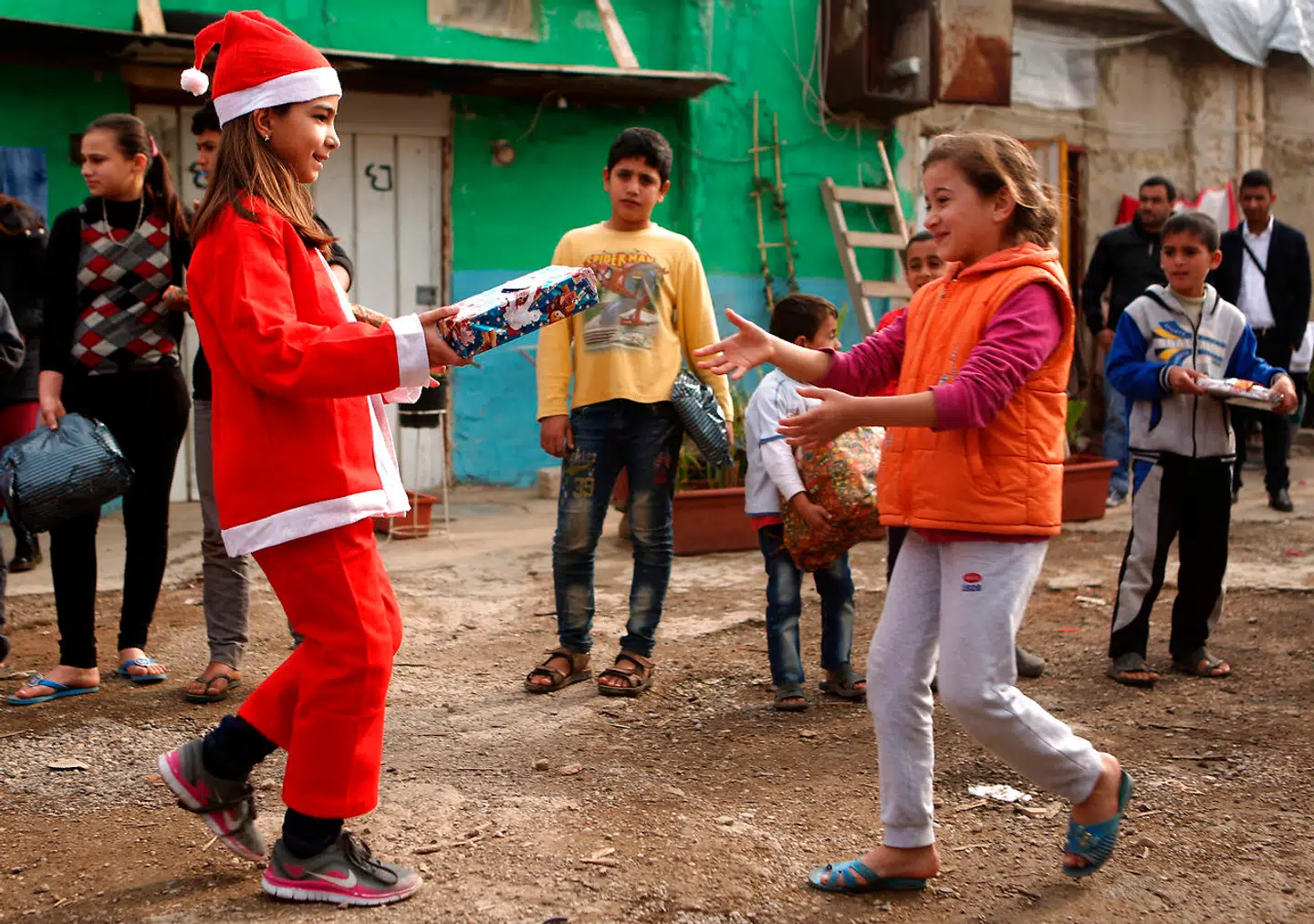 Man kan vel kun være glad, hvis man har lært sit barn at hjælpe andre - men det kan alligevel være lidt angstprovokerende, at ens voksne datter tager væk over julen for at arbejde i en flygtningelejr. Her er det Chloe, en kristen libanesisk teenager, som har klædt sig ud som julemanden, og giver en syrisk flytgning en gave. Billedet er taget i 2016 i byen Dbayeh nord for Beirut. Foto: PATRICK BAZ / AFP